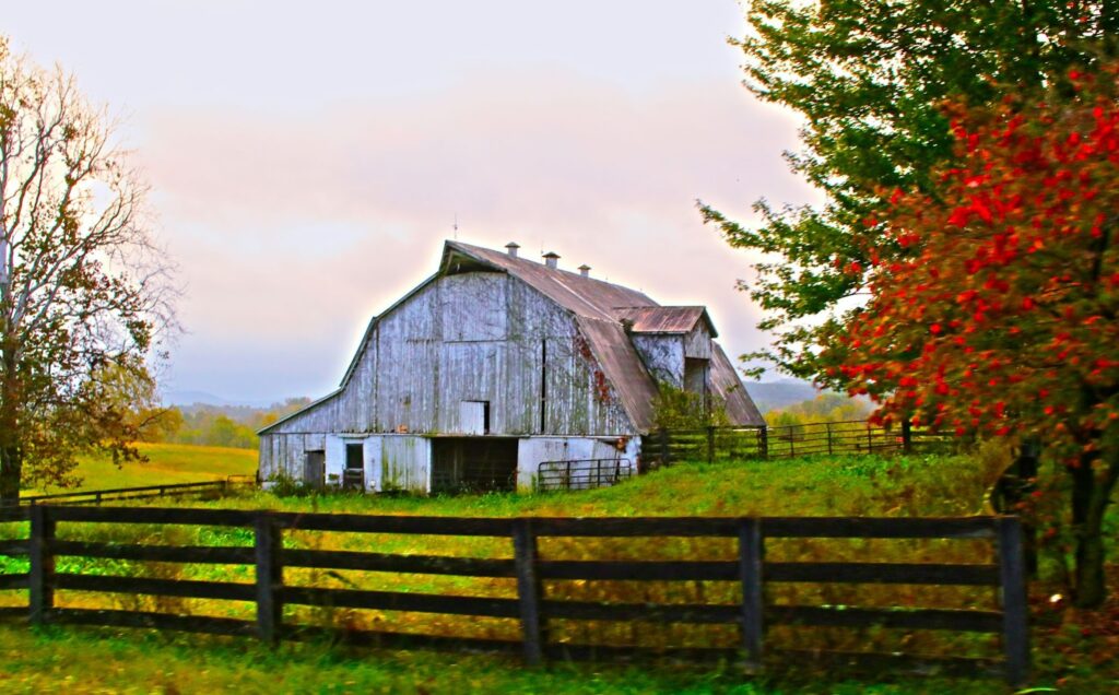 A red barn with a fence on a farm.