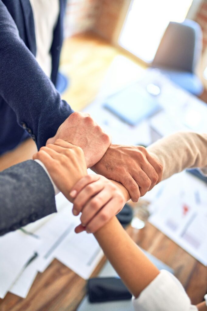 Four people lock hands together at a meeting.